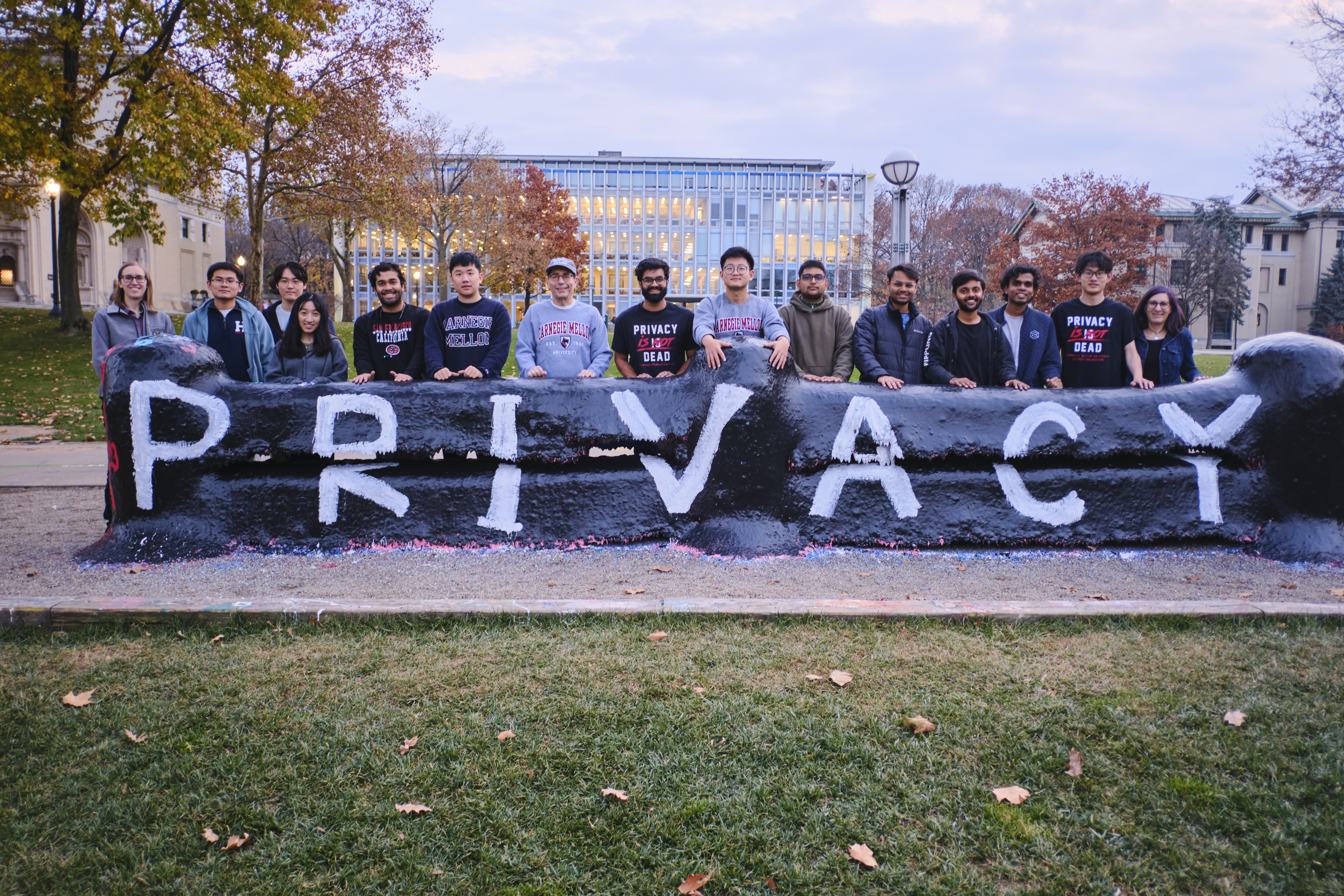 Privacy Engineering students and faculty at the CMU fence, painted with the word 'PRIVACY'